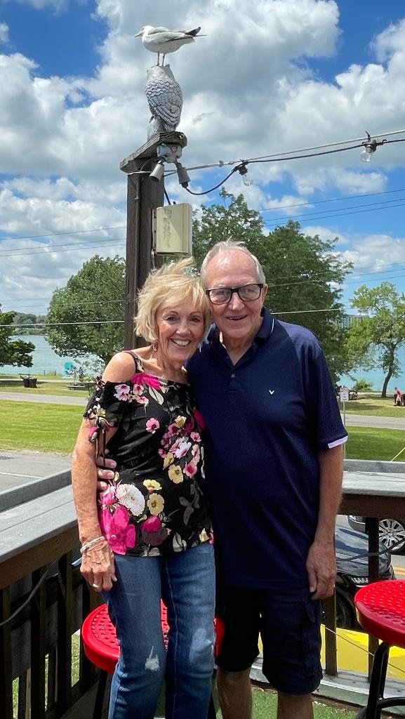 Judi and Dave Zettel smiling together outdoors by the water