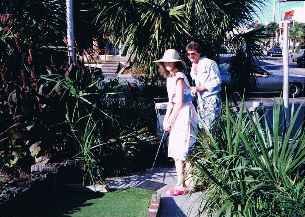 Couple playing mini golf tropical setting