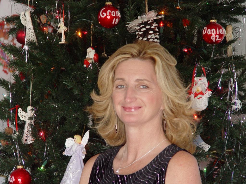 Woman smiling in front of Christmas tree