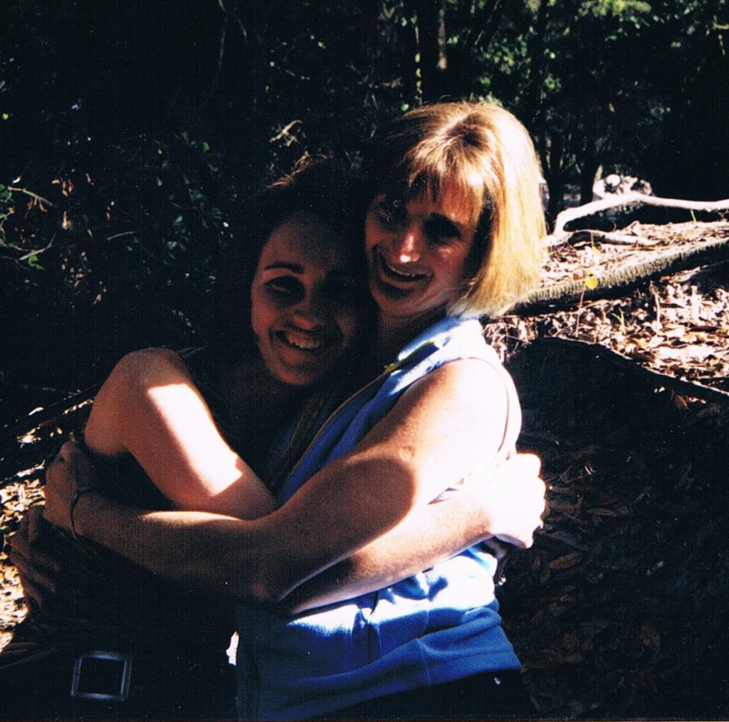 Two women hugging outdoors in woods