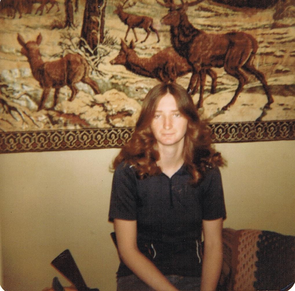 Young woman sitting indoors vintage deer tapestry
