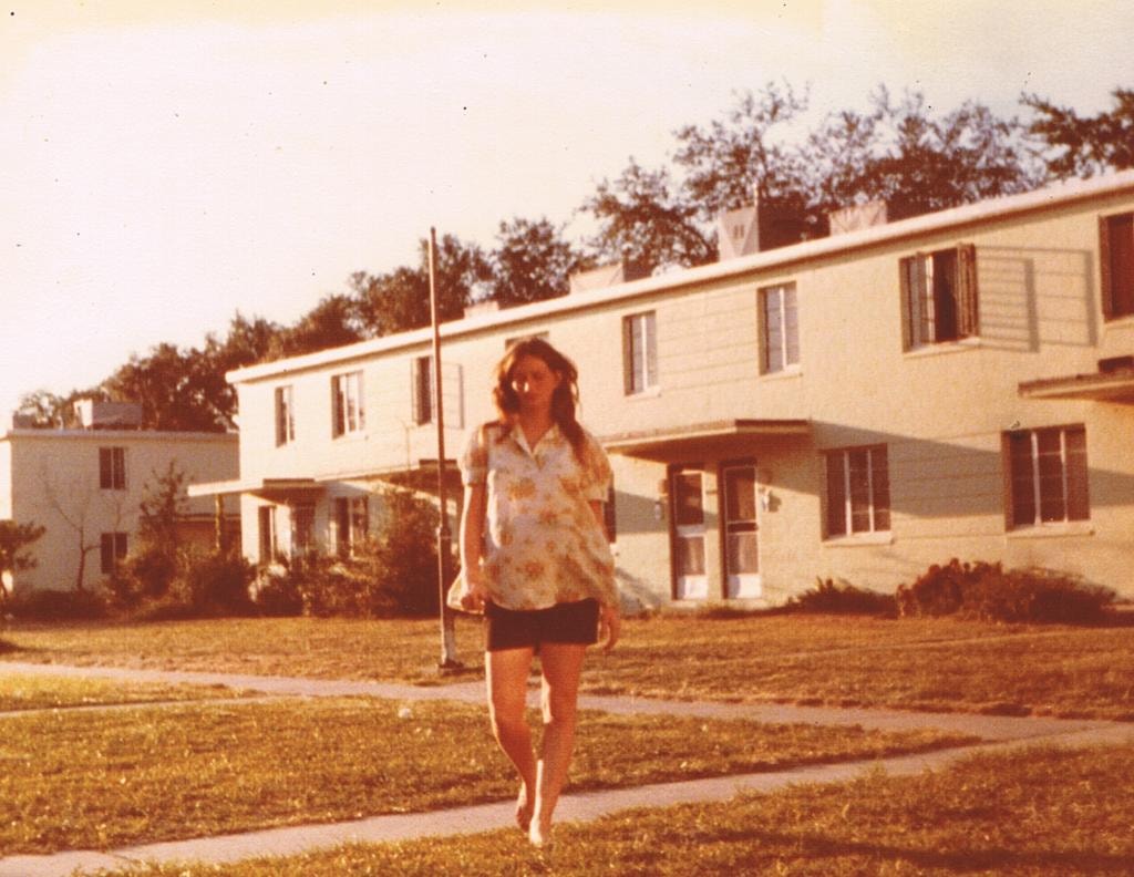 Young woman walking in front of apartment buildings vintage