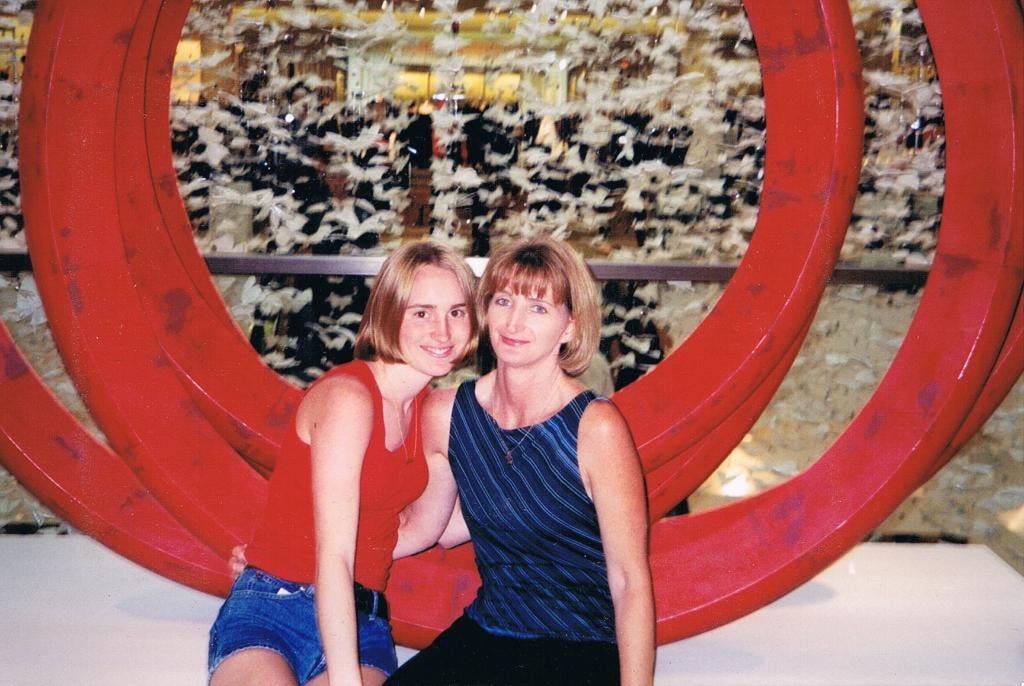 Two women posing in front of red circular sculpture