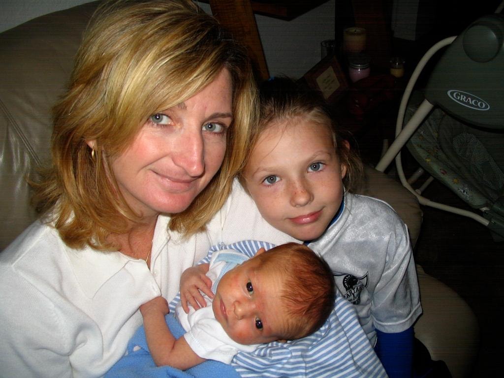 Woman with two children including newborn on couch