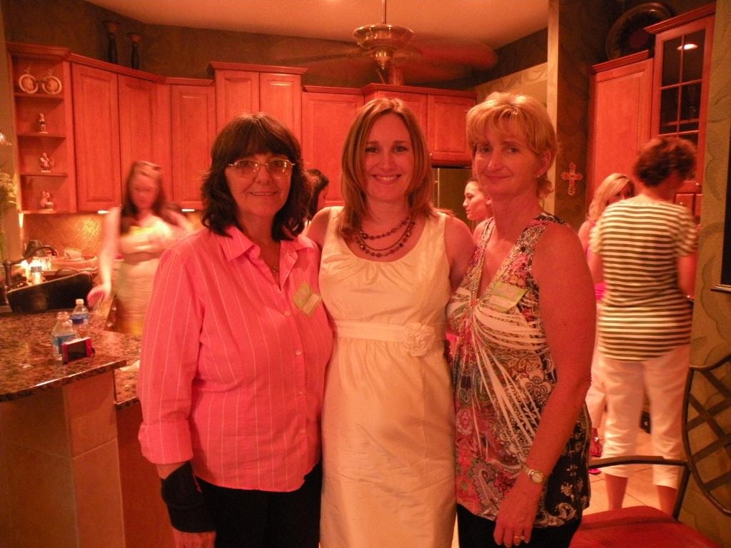 Three women posing together at indoor gathering