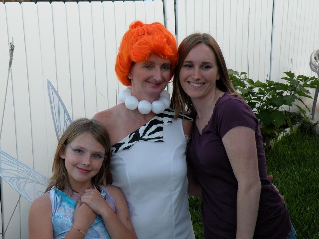 Three people in costume Wilma Flintstone and fairy outdoors