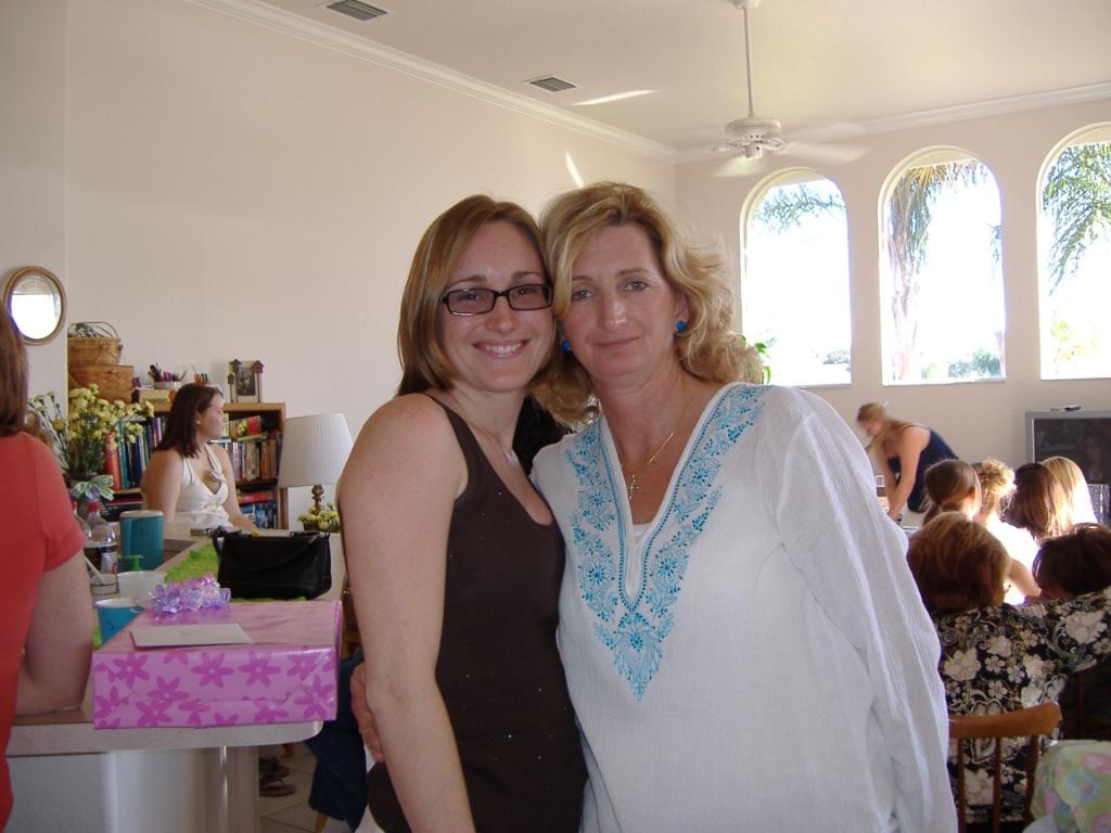 Two women smiling at indoor gathering bright room