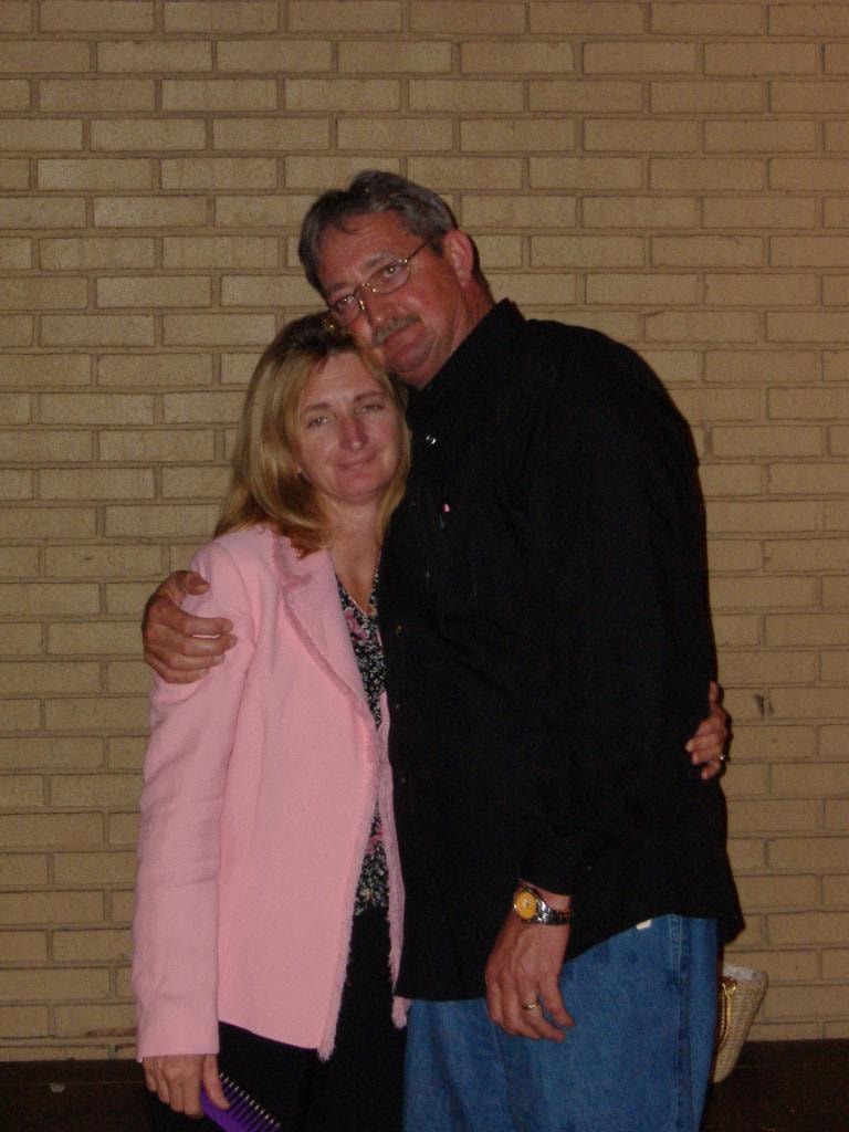 Couple posing together in front of brick wall