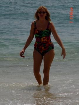 Woman walking out of ocean in floral swimsuit