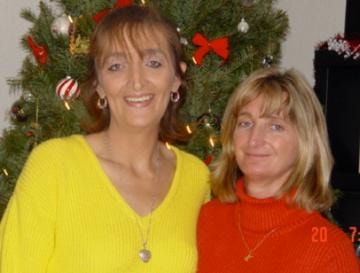 Two women in sweaters in front of Christmas tree