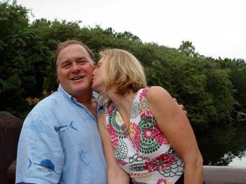 Woman kissing man on cheek outdoors by water
