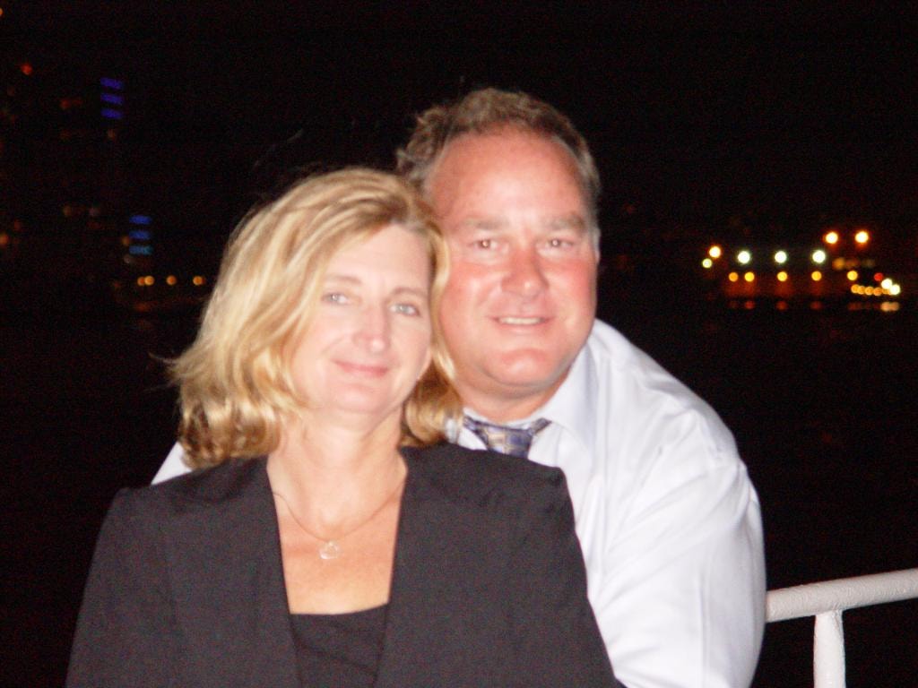 Couple dressed up posing on boat at night city lights