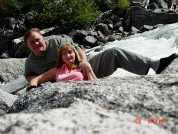 Couple relaxing on rocks by mountain stream