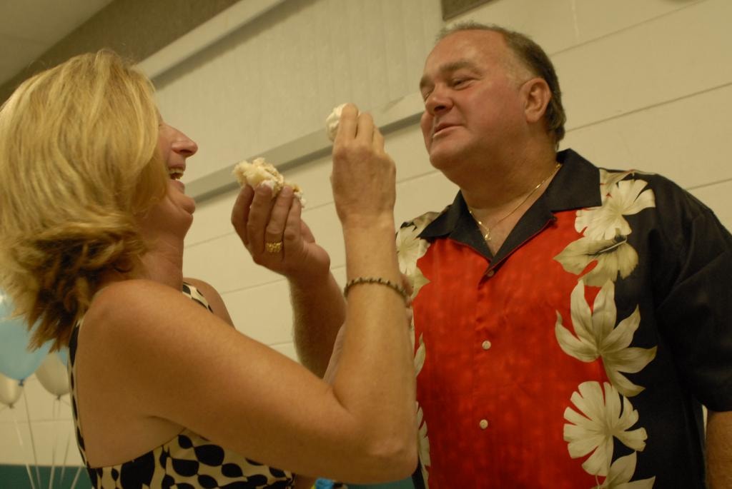 Couple feeding each other cake at celebration with balloons